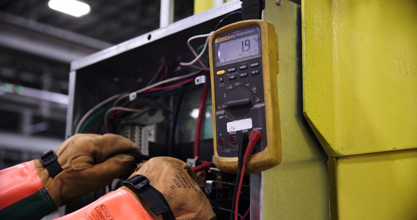 Hands taking electrical measurements with a multimeter